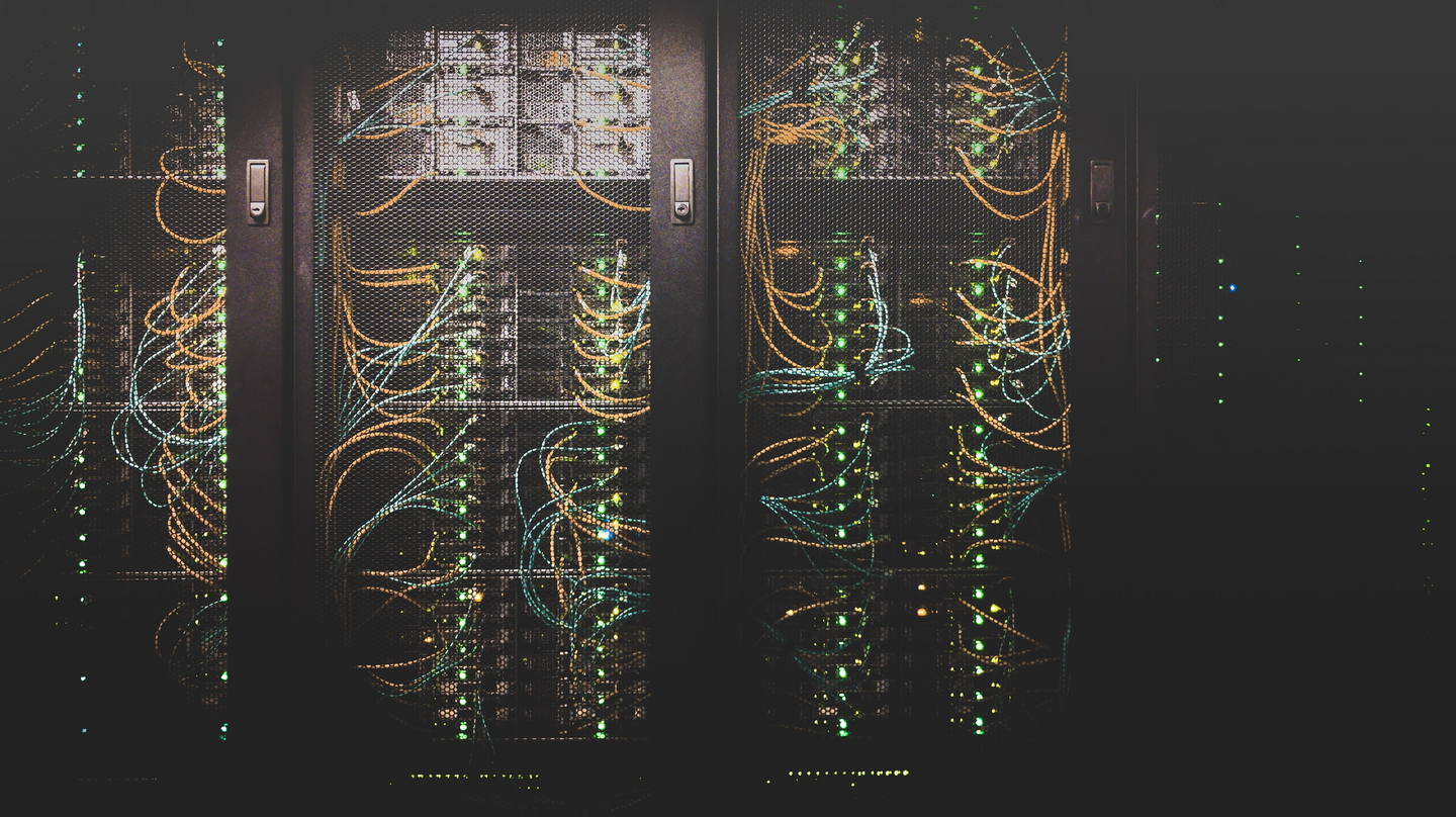 Drei Serverracks in einem dunklen Raum mit leuchtenden Kabeln und Blinklichtern.